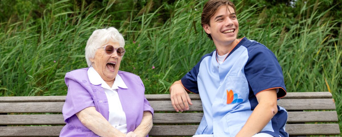 Collega met oudere vrouw buiten op bankje