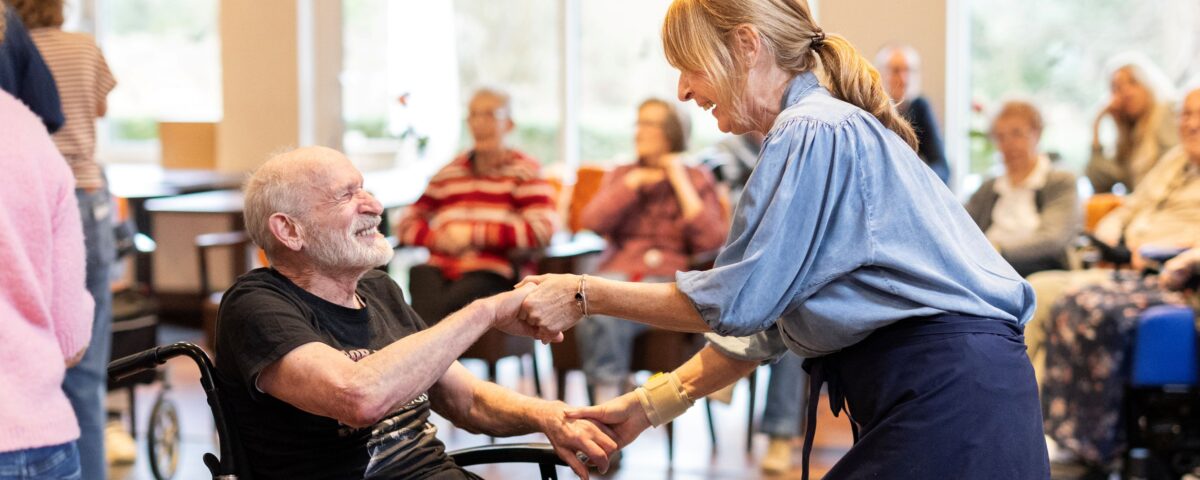 Collega met man in rolstoel aan het dansen