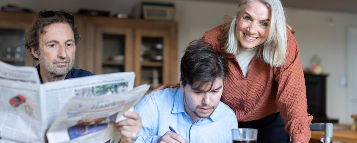 Drie mensen aan tafel met de krant