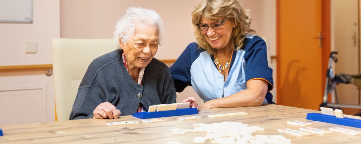 Collega met oudere vrouw aan het rummikubben