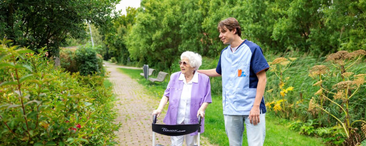 Collega met oudere vrouw en loopkar buiten