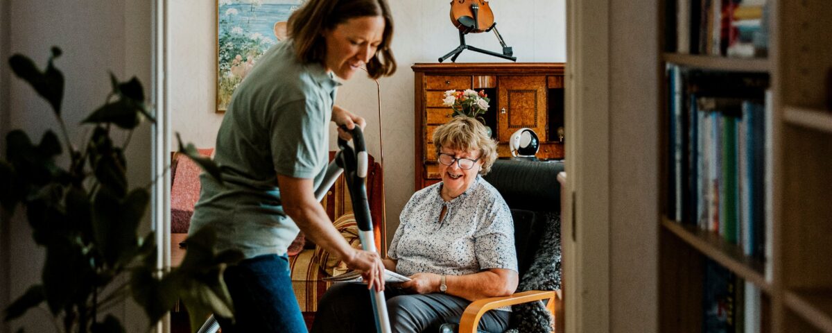 Vrouw is aan het stofzuigen in woning oudere vrouw