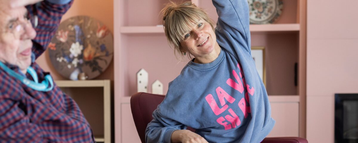 Vrouw met oudere man in rolstoel aan het rekken