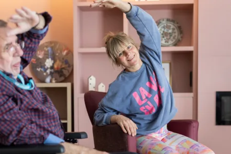Vrouw met oudere man in rolstoel aan het rekken