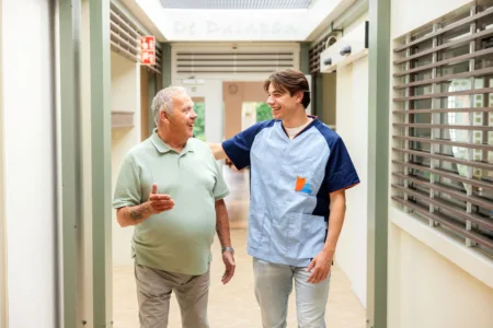 Collega met meneer in gang verpleeghuis