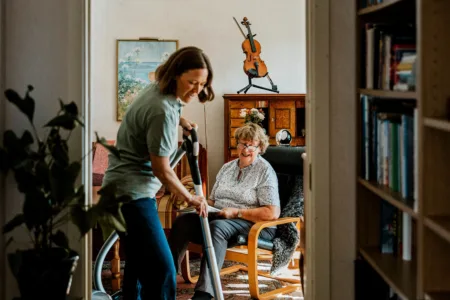 Vrouw is aan het stofzuigen in woning oudere vrouw