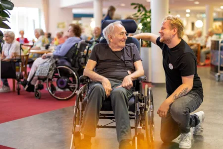 Collega binnen met oudere man in rolstoel