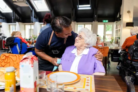 Collega omhelst oudere vrouw in restaurant