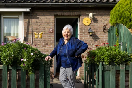 Oudere vrouw voor haar woning