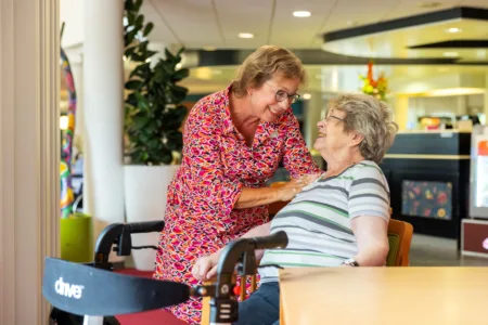 Collega met oudere vrouw en loopkar