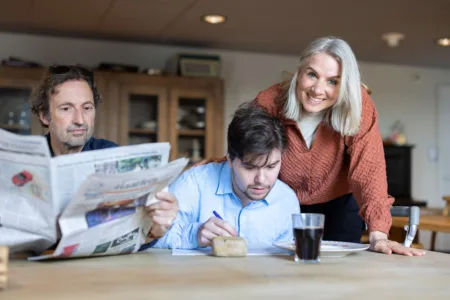 Drie mensen aan tafel met de krant