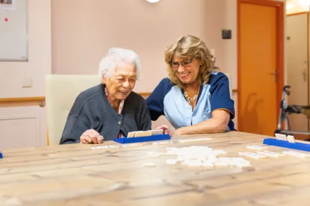 Collega met oudere vrouw aan het rummikubben