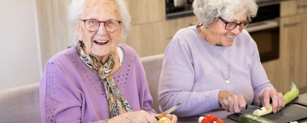Twee oudere vrouwen zijn groente aan het snijden