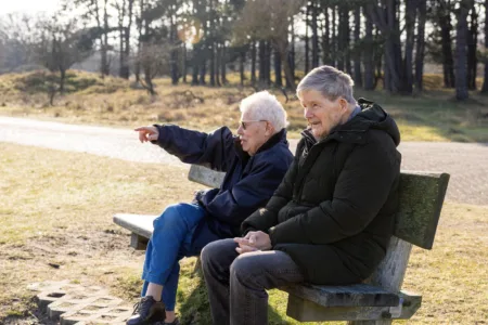 Twee oudere mensen buiten op een bankje in de duinen