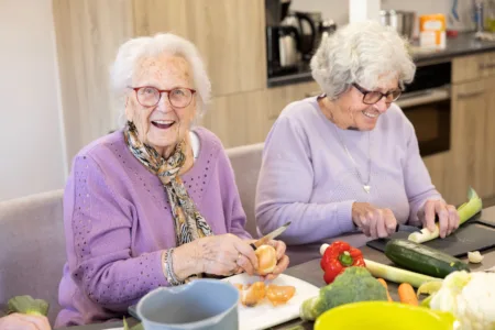 Twee oudere vrouwen zijn groente aan het snijden