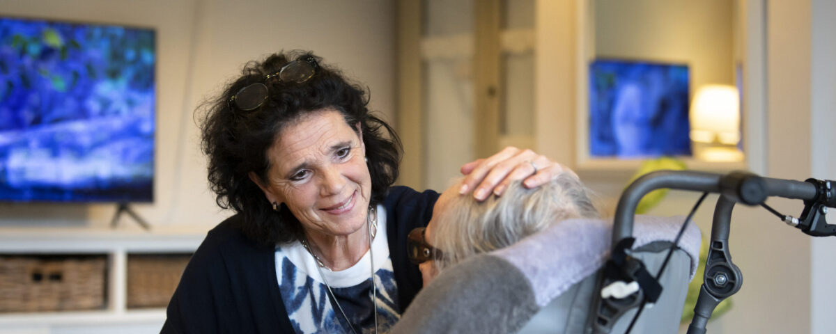 Vrouw houdt haar hand op het hoofd van vrouw in rolstoel
