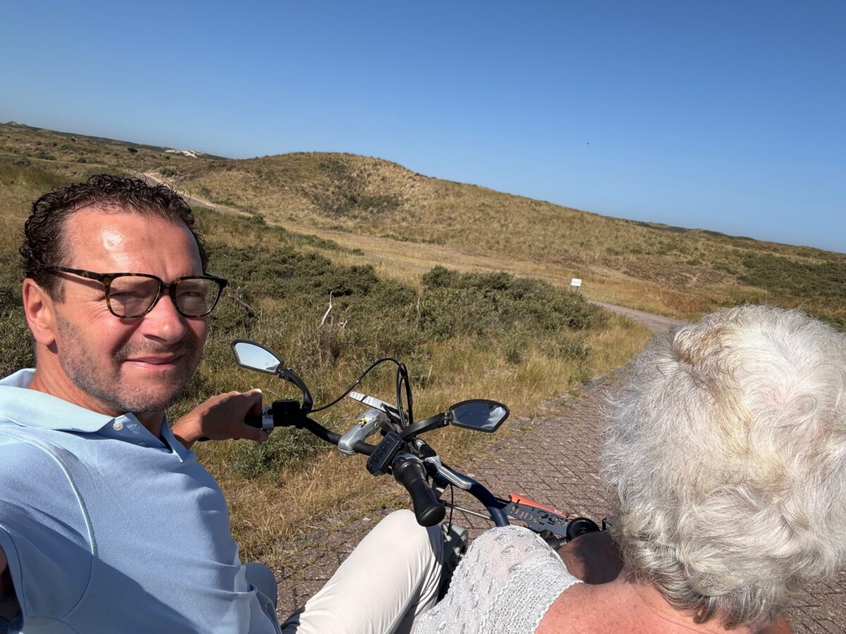 Bestuurder en cliënt op de duofiets in de duinen