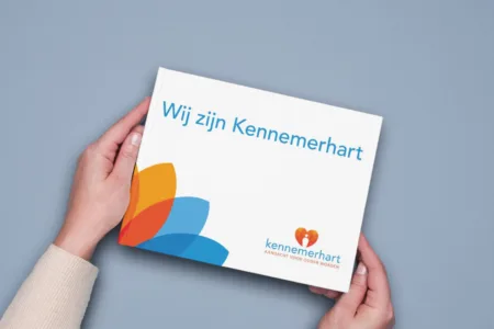 Twee handen houden een boek met tekst 'Wij zijn Kennemerhart' vast