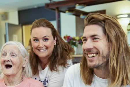 Oudere vrouw zit lachend met twee jonge mensen