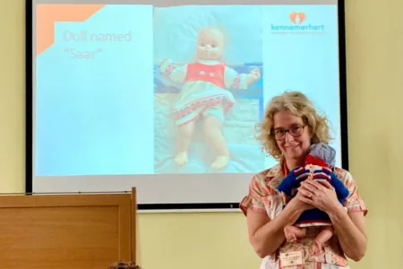 Persoon geeft een presentatie met zorgpoppen