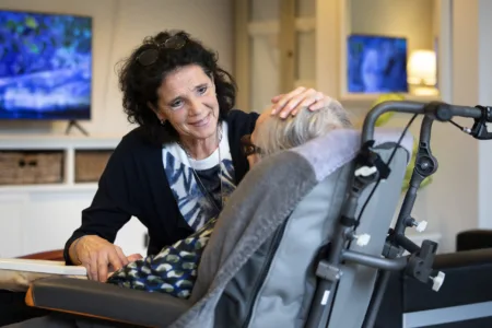 Vrouw houdt haar hand op het hoofd van vrouw in rolstoel