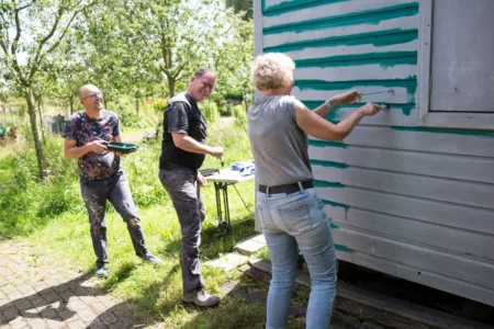 Drie mensen lachend aan het verven